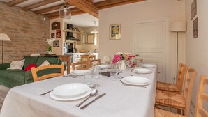A dining area with a table set for six, wooden chairs, and a kitchen in the background.