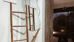 Ein modernes Interieur mit minimalistischem Design, inklusive einer Holzleiter, einem großen Spiegel und einem kleinen Hocker.