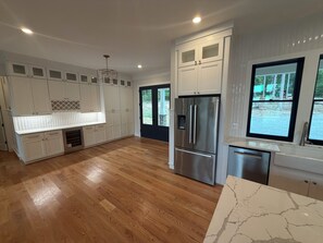 A modern kitchen with white cabinetry, a stainless steel refrigerator, and a marble countertop. - LICENSE TO CHILL II Spacious 8-bedroom Lake Anna house. (Bumpass)