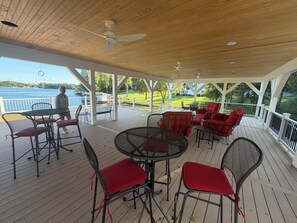 Une terrasse extérieure couverte, dotée d’un espace salon et offrant une vue sur un plan d’eau.