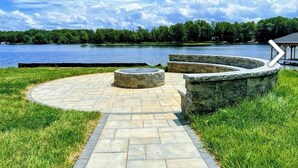 Une terrasse en pierre avec un espace de détente circulaire et une vue sur un lac.