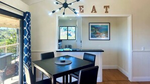 A dining area with a table and chairs, a kitchen in the background, and a balcony with a view. - 2-story Hilltop Penthouse & Grove View Suite (San Diego County)