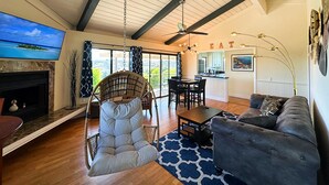A spacious living room with a fireplace, a large television, a dining area, and a kitchen in the background. - 2-story Hilltop Penthouse & Grove View Suite (San Diego County)