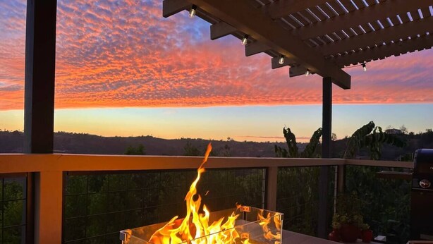 A fire feature on a balcony with a view of the sunset. - 2-story Hilltop Penthouse & Grove View Suite (San Diego County)