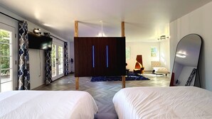 A modern bedroom with two beds, a large mirror, a TV, and a wardrobe. - 2-story Hilltop Penthouse & Grove View Suite (San Diego County)
