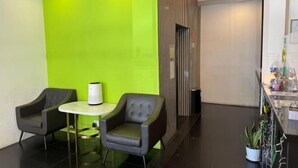 A modern lobby with two leather armchairs, a small round table, and a bright green accent wall. - Lodge 5 (Kota Kinabalu)