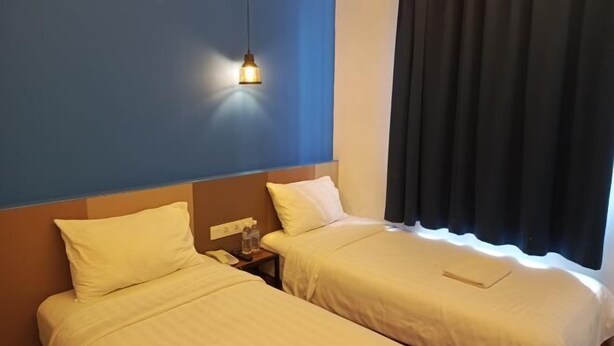 A hotel room with two beds, a nightstand, a lamp, and a window with curtains. - Lodge 5 (Kota Kinabalu)