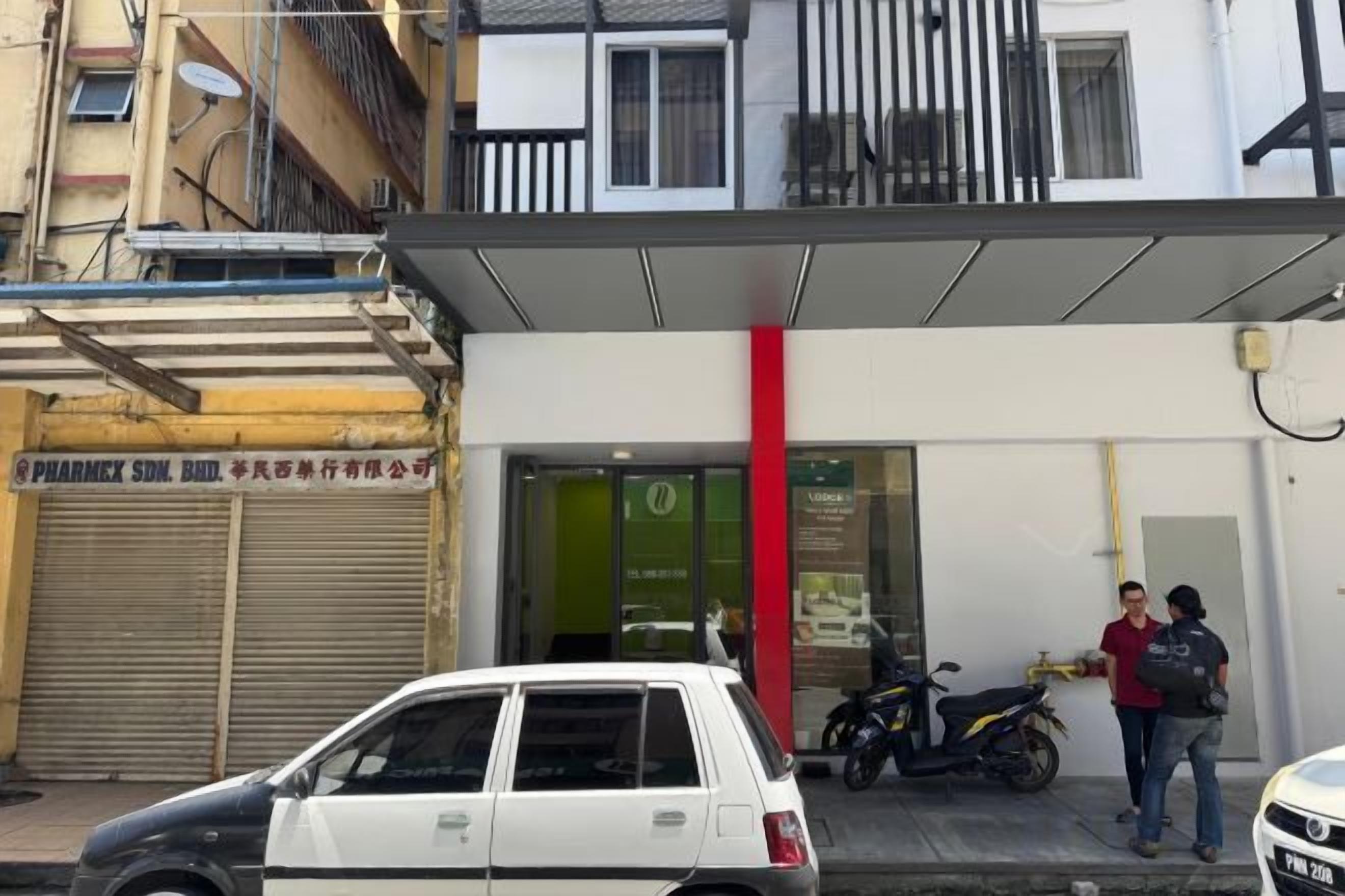 A building with a pharmacy on the ground floor, a covered entrance, and a parked motorcycle.