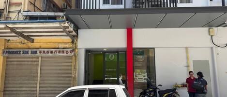 A building with a pharmacy on the ground floor, a covered entrance, and a parked motorcycle.