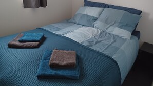 A single bed with blue bedding and two folded towels. - Cozy detached vacation home with garden around: de Frije Fûgel, Lauwersoog (Lauwersoog)