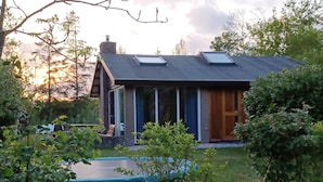 A modern house with a sloped roof, large windows, and a visible chimney. - Cozy detached vacation home with garden around: de Frije Fûgel, Lauwersoog (Lauwersoog)