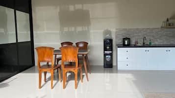 A modern kitchen with a dining table and chairs, a coffee machine, and a white cabinet.