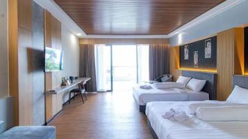 Quarto de hotel com duas camas, uma escrivaninha, televisão e vista para o exterior.