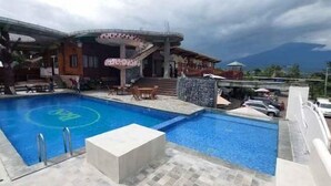 Una piscina con diseño circular, un área de estar cubierta y vistas a la montaña.