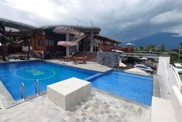 A swimming pool with a circular design, a covered seating area, and a view of a mountain.