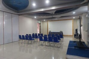 A conference room with rows of blue chairs, a whiteboard, and a projection screen. - Azana BeSt Hotel Batu (Junrejo)