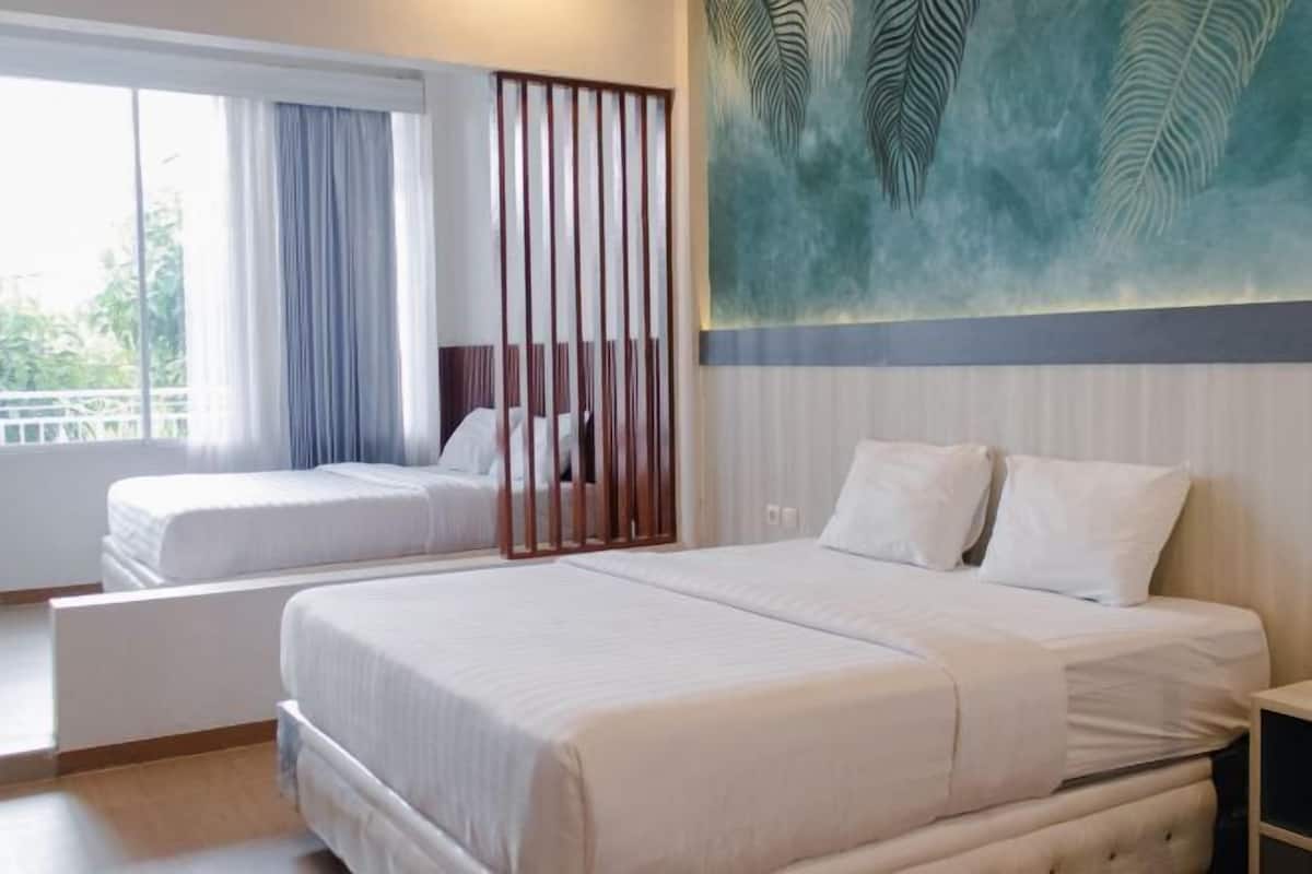Habitación de hotel con dos camas, un ventanal grande y un cuadro con hojas.