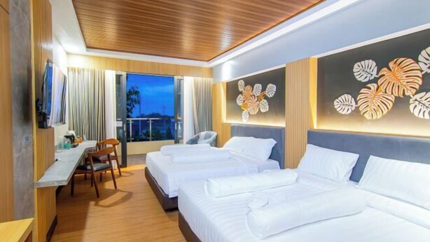 Habitación de hotel con dos camas, un escritorio y una silla. Se ve el exterior a través de la ventana.