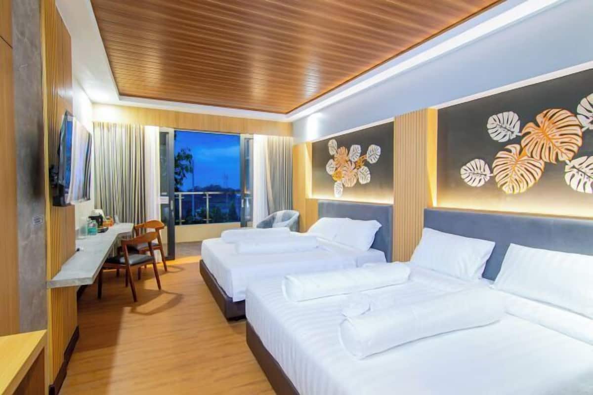 Habitación de hotel con dos camas, un escritorio y una silla. Se ve el exterior a través de la ventana.