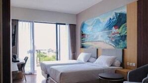 Una habitación de hotel con cama, escritorio, silla, una mesita y un cuadro en la pared.