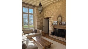 A cozy living room with a stone wall, a fireplace, a sofa, and a coffee table. - Luxurious 5-bedroom castle in peaceful Rayet with AC (Rayet)