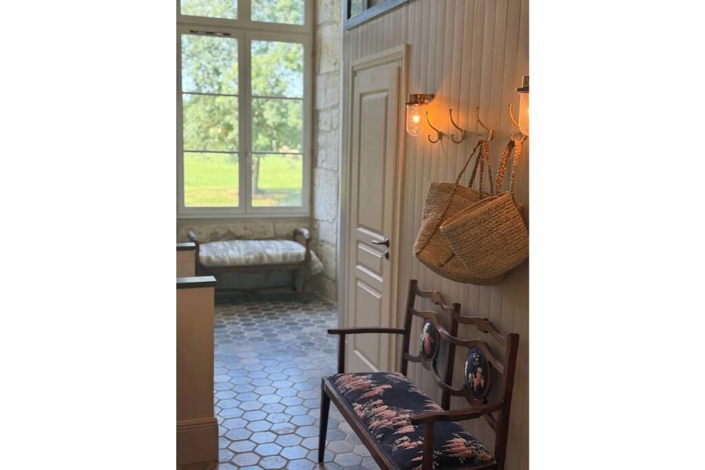 A hallway with a bench, a door, and a wall-mounted light fixture.