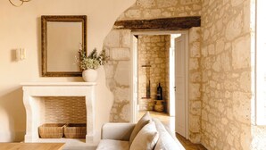 A cozy living room with a fireplace, a sofa, a wooden table, and a stone wall. - Luxurious 5-bedroom castle in peaceful Rayet with AC (Rayet)