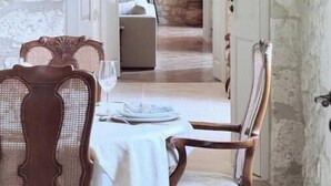 A dining area with a stone wall, a wooden ceiling, and a view into a bedroom with a bed and a fireplace. - Luxurious 5-bedroom castle in peaceful Rayet with AC (Rayet)