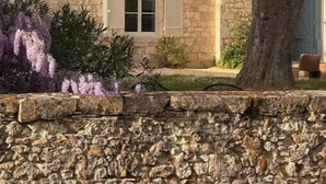 A stone building with two windows and shutters, surrounded by greenery and a tree. - Luxurious 5-bedroom castle in peaceful Rayet with AC (Rayet)