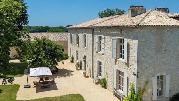 A stone building with a tiled roof, a covered outdoor seating area, and a clear sky. - Luxurious 5-bedroom castle in peaceful Rayet with AC (Rayet)
