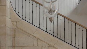 Eine Steintreppe mit schwarzem Geländer und einer hängenden Leuchte.