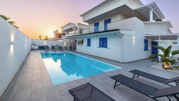 A modern two-story building with a swimming pool, outdoor seating, and a balcony. - ONDA BIANCA LUXURY APARTMENTS (Realmonte)