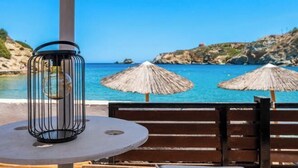 A beachside seating area with a round table, a metal lantern, and two thatched umbrellas. - BlueGreen Holiday Homes: Holidays with Seaview (Malevizi)