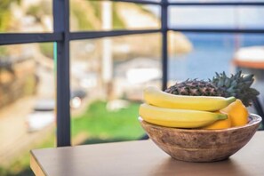 A wooden bowl with bananas and a pineapple on a table by a window. - BlueGreen Holiday Homes: Holidays with Seaview (Malevizi)