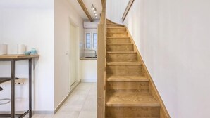 A staircase leading to a kitchen area with white walls and a wooden floor. - BlueGreen Holiday Homes: Holidays with Seaview (Malevizi)
