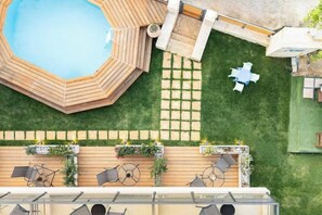 Un área de piscina en la azotea con un jacuzzi, mobiliario exterior y un jardín.