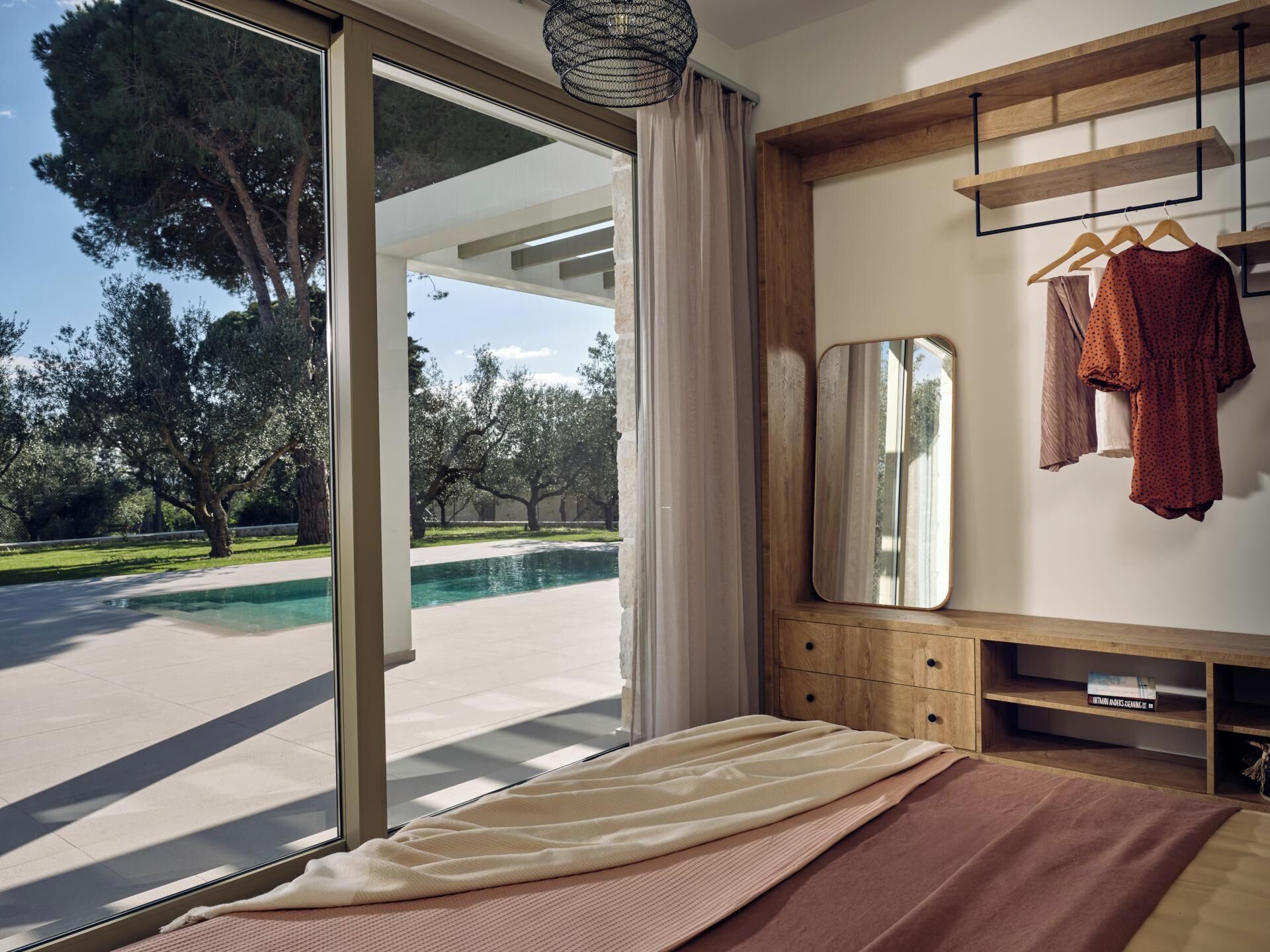 Une chambre avec une grande fenêtre donnant sur une piscine et des arbres.