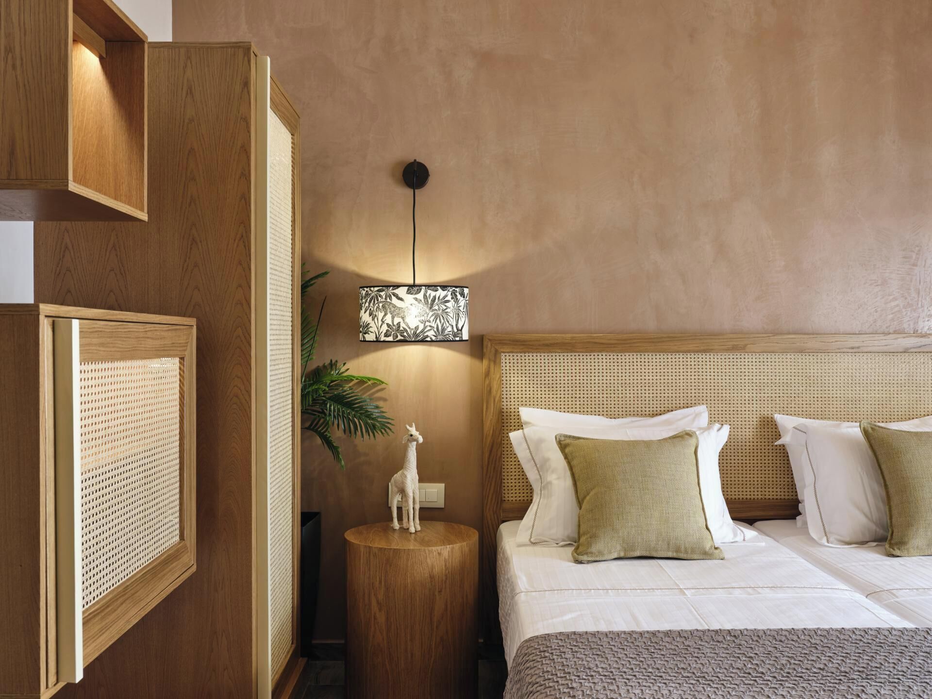 A hotel room with a bed, a nightstand, a lamp, and a wall-mounted shelf.