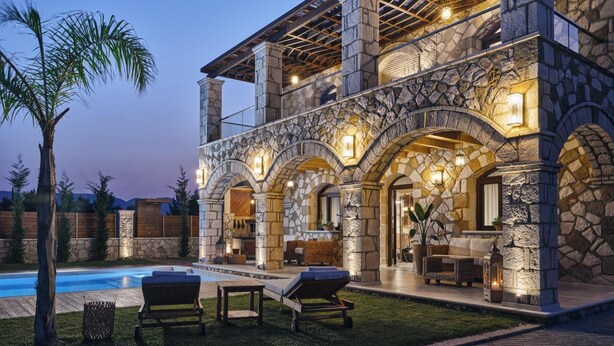 A stone-clad house with a pool, outdoor seating, and a well-lit interior. - Casa Di Pietra - Four Bedroom Villa, Sleeps 8 (Zakynthos)