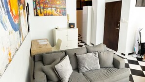 Un salón moderno con un sofá gris, una mesa de centro de madera y un suelo a cuadros en blanco y negro.