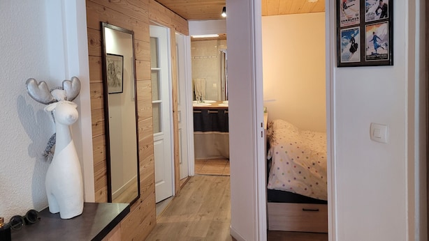 Un pasillo con paredes de madera, un espejo, una cama con colcha de lunares y un cartel en la pared.