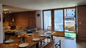 Un comedor con una mesa de madera preparada para cuatro, un sofá y una pared de madera.