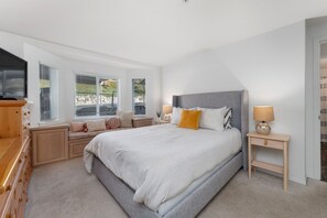 Une chambre à coucher avec un grand lit, des tables de chevet, une commode et un téléviseur.
