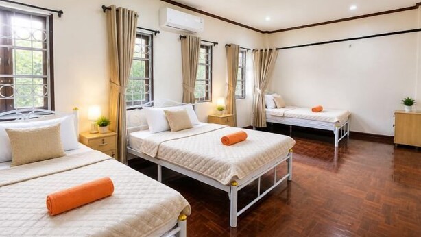 A hotel room with three beds, wooden flooring, and large windows with curtains. - The Star Home (Bangkok)