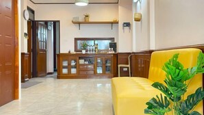 A hotel lobby with a reception desk, a yellow sofa, and a potted plant. - The Star Home (Bangkok)