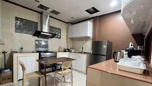 A compact kitchen with a central island, a stove, and a refrigerator. - The Star Home (Bangkok)