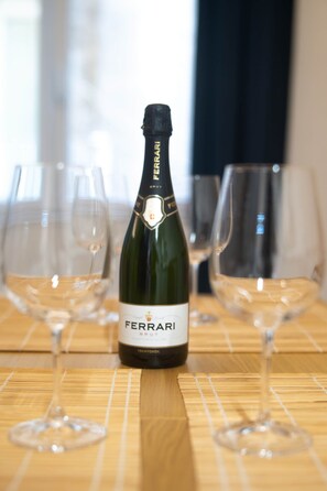 Een fles Ferrari Brut wijn op een houten tafel met drie lege wijnglazen.