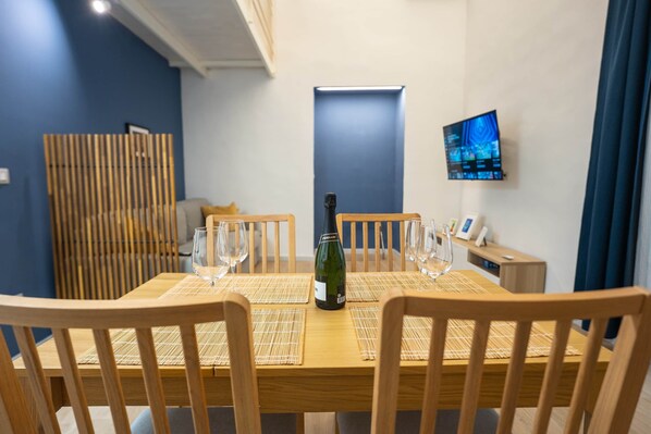 A dining table with four chairs, a bottle of wine, and three wine glasses.