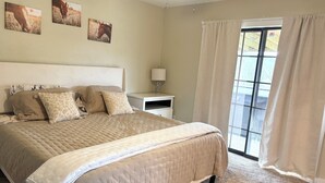 A bedroom with a large bed, a nightstand, a lamp, and a window with curtains. - Wild Horses/ Scenic Ranch Retreat (Bucyrus)