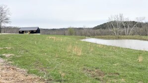 A rural landscape with a pond, a black building, and a grassy field. - Wild Horses/ Scenic Ranch Retreat (Bucyrus)